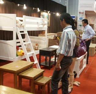 Customers watch beds, desks and chairs displayed at a HCMC-based furniture shop (Photo:cafef.vn)