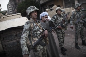 An Egyptian man stands next to army troops stationed in central Cairo on January 29, 2011. AFP