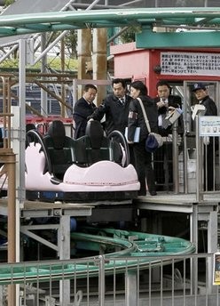 Police investigators examine a spinning roller coaster after a man fell from that to his death at the Tokyo Dome City Attractions Sunday, Jan. 30, 2011 in Tokyo.