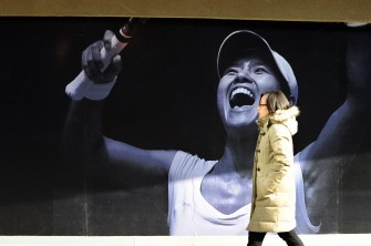 A woman walks past an image of a jubilant Chinese tennis star Li Na outside a sporting goods store in Beijing on January 31, 2011. AFP