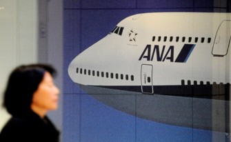 AFP - A woman walks past a picture showing a Japan's All Nippon Airways (ANA) Boeing 747 at its headquarters in Tokyo on January 31, 2011.