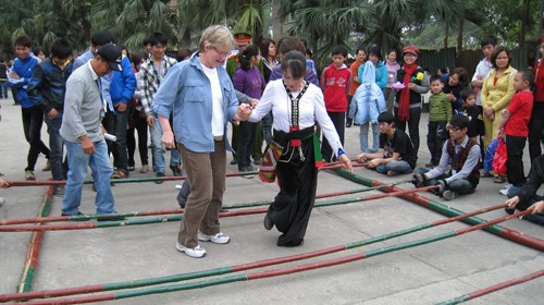 A Thai minority girl instructs a foreign visitor to play bamboo dance at the museum (Photo: Tuoi tre)