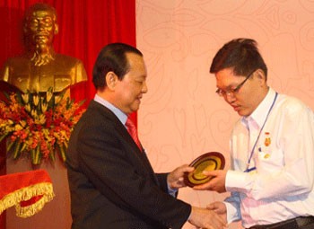 Mr. Le Thanh Hai, Secretary of the HCM City Party Committee (L), gives a medal to a Chinese Vietnamese people in the ceremony.