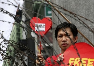 A protester displays a heart-shaped cutout with a message during a rally near the Presidential Palace in Manila, Philippines, on Valentine's Day Monday Feb. 14, 2011