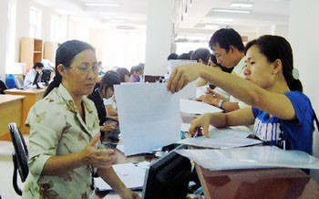 An employee (R) guiding a woman at the HCMC Social Insurance Company (Photo: SGGP)