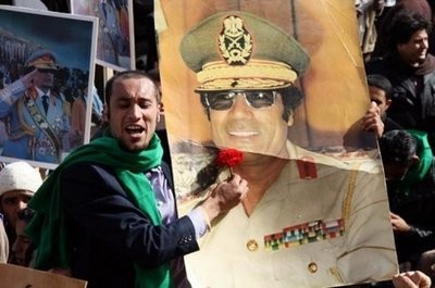 A pro-government supporter holds a portrait of Libyan leader Moamer Kadhafi during a gathering in Tripoli on February 16, 2011