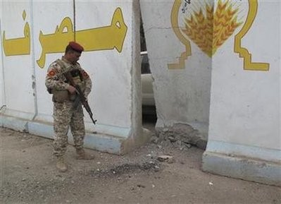 An Iraqi soldier stands guard as he looks at a damaged concrete wall after a bomb attack in Baghdad March 23, 2010
