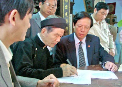Researcher Phan Thuan An (C) signs a pledge to give the Ministry of Foerign Affairs a document during the reign of Bao Dai related to Paracel Islands in Dec. 25, 2009.