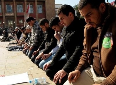 Demonstrators pray in front of the parliament building in Rabat, Morocco.