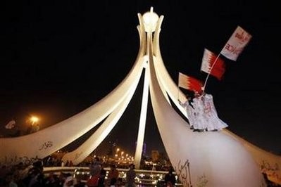 Protesters wave Bahraini national flags after they climb up onto the Pearl Roundabout as they celebrate in Pearl Square in the capital Manama February 19, 2011.