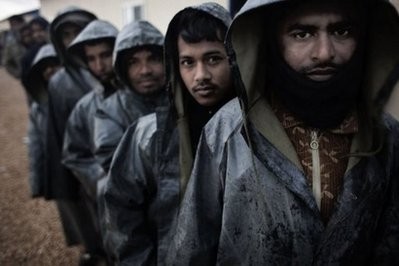 AFP - Stranded foreign workers queue for breakfast under pouring rain in the port of Benghazi.
