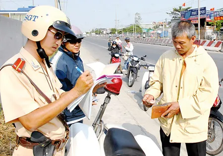 CSGT đội An Lạc lập biên bản người vi phạm luật giao thông trên quốc lộ 1A vào sáng 8-2. Ảnh: KIM NGÂN