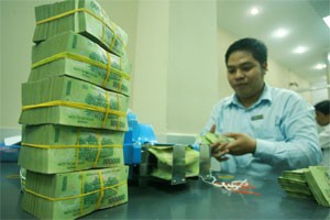 A cash teller at Asia Commercial Bank piles up cash. Bank interest rates are expected to increase on the government’s tight monetary policy (Photo: Minh Tri)