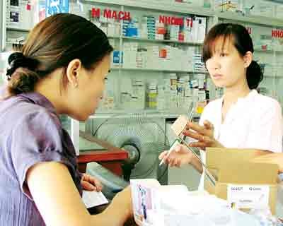 A customer is reading an announcement to hike prices of distributors on a cell phone of the pharmacy assisstant (Photo: SGGP)