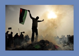 A resident of the north-central Libyan city of Benghazi stands atop a burning heap of books authored by Libyan leader Moamer Kadhafi. AFP