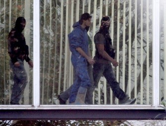 AFP- Police officers escort a man in a blue overall along a corridor at the German Federal Supreme Court in Karlsruhe, Germany, 3 March 2011. German investigators said on March 3, 2011 they suspected a Kosovan man arrested for the fatal shooting of two US airmen on their bus at Frankfurt airport is an Islamist. AFP