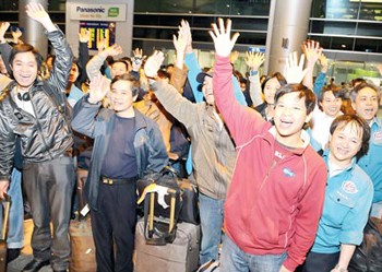 Evacuated Vietnamese workers wave hello upon their arrival at Tan Son Nhat Airport in HCMC on March 7, 2011. (Photo: SGGP)