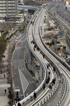 Yurikamome train passengers walk on the elevated track towards Shiodome Station in Tokyo near Tokyo Bay Friday, March 11, 2011, shortly after a 7.9-magnitude earthquake has struck off Japan's northeastern coast