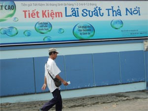 A man walks by a board read "free-floating saving rate" of a HCMC-base brach of Asia Commercial Bank. The increase in reserve repurchase, refinancing and rediscount rates will lower this year’s earning result, banks say (Photo:Minh Tri)