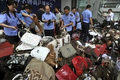 In this Aug. 16, 2010 file photo, Chinese business administration officers cut fake luxury branded handbags during a mass elimination of counterfeit products in southwest China's Chongqing city