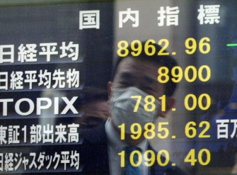 A businessman is reflected on a share prices board as he watches the sharply dropped figure of the Tokyo Stock Exchange in Tokyo on March 15, 2011. AFP