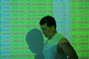 A man walks by a projector screen showing share prices at a HCMC-based brokerage. Investors remain unwilling to enter the market in spite of many share prices falling significantly (Photo:Minh Tri)