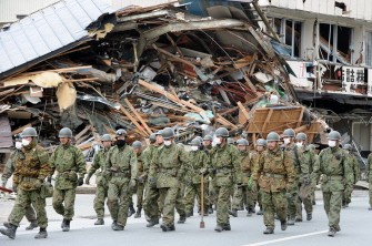 Japanese Self-Defense Force soldiers walk past destroyed buildings in the city of Ofunato, Iwate prefecture on March 15, 2011. AFP