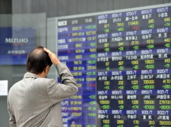 A pedestrian gazes at a share prices board in Tokyo on March 15, 2011. AFP