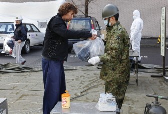 A Self Defense Force personnel receives a plastic bag containing clothing potentially contaminated by radiation from a resident in Nihonmatsu city, Fukushima prefecture, on March 16, 2011. AFP