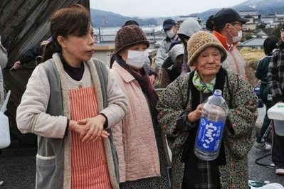 People wait for water at a distribution point in Ofunato