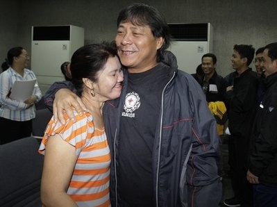 Rafael Macalindong, a Filipino crewman who survived the tsunami in Japan, right, hugs his wife Myrna as he arrives together with 19 other seafarers at Manila's International Airport, Philippines on Wednesday, March 16, 2011