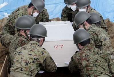 Japan Ground Self Defense Force prepare to lay a coffin during a burial ceremony for the March 11 tsunami victims in Higashimatsushima City, Miyagi Prefecture, Japan, Wednesday, March 23, 2011.