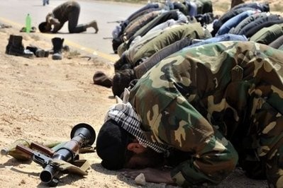 AFP - Libyan rebels pray on the road to Ajdabiya.