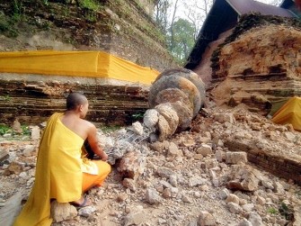 A Thai Buddhist monk inspects a fallen stupa of the Chedi Luang pagoda a day after a strong earthquake struck Myanmar near the Thai border, in the Chiang Saen district of Thailand's northern Chiang Rai province on March 25, 2011. AFP