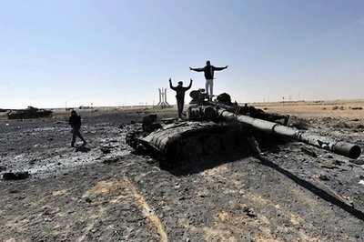 Libyan rebels celebrate on a destroyed tank in the strategic oil town of Ajdabiya
