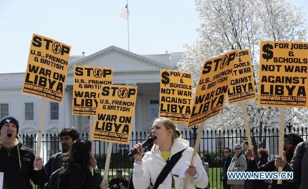 Demonstrators hold placards to protest against the U.S. military intervention in Libya outside the White House in Washington D.C., capital of the United States, March 26, 2011.