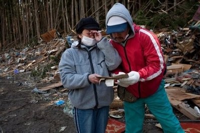 A woman sobs with her husband after finding her missing grandmother's old photos among the debris in tsunami-hit Miyagi prefecture on March 28, 2011.