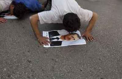 Syrian workers living in Lebanon kiss posters of President Bashar al-Assad laid out on the ground in front of the Syrian embassy in Beirut March 28, 2011