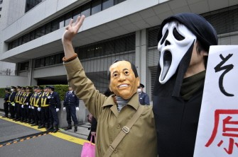 AFP - A protestor wears a mask resembling Prime Minister Naoto Kan as protesters gather against nuclear plants, in front of the Tokyo Electric Power Co (TEPCO) headquarters in Tokyo on March 27, 2011.