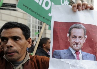 A man holds up an altered image of French President Nicolas Sarkozy during a demonstration in support of Libyan leader Moamer Kadhafi in London, on March 29, 2011. AFP