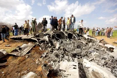 Người dân Libya nhìn xác máy bay F-15E của Mỹ rơi gần thị trấn Benghazi, cứ điểm của lực lượng nổi dậy Libya, ngày 22-3. Thông báo của quân đội Mỹ cho biết máy bay rơi vì lý do kỹ thuật và nguyên nhân cụ thể đang được điều tra. Bộ Tư lệnh Mỹ ở châu Phi, đơn vị chỉ huy chiến dịch tại Libya, cho biết 2 phi công đã nhảy dù an toàn ra khỏi máy bay. Do rơi tại vùng của các tay súng nổi dậy, 2 phi công được đối xử tốt và cả hai đã được lực lượng liên quân đưa ra khỏi Libya. (Ảnh Washington Post)