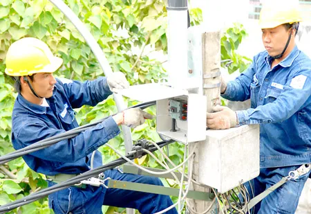 Nhân viên Công ty Điện lực Sài Gòn gắn tụ bù giúp giảm hao phí điện. Ảnh: KIM NGÂN