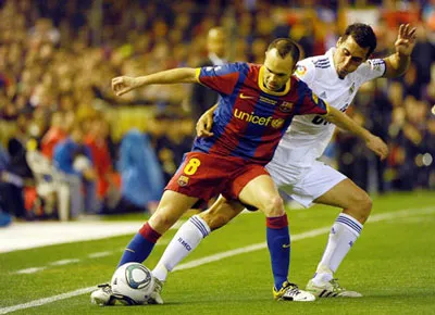 Tiền vệ Iniesta (trái, Barcelona) che bóng trước hậu vệ Arbeloa của Real Madrid.