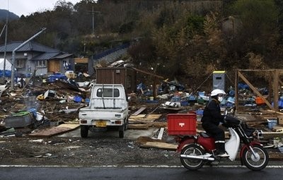 Mail carrier Kenjiro Ishimori rides a motorcycle after delivering mails at an area devastated by the March 11 earthquake and tsunami in Ishinomaki, Miyagi Prefecture, northeastern Japan, Saturday, April 30, 2011