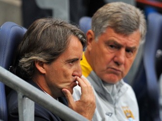 Roberto Mancini (L) sits with his assistant Brian Kidd before the match between Manchester City and Tottenham Hotspur