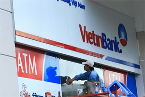 A man cleans the door of a HCMC-based branch of Vietinbank. Equitized banks will grapple to find local strategic partners due to high requirements (Photo:Minh Tri)