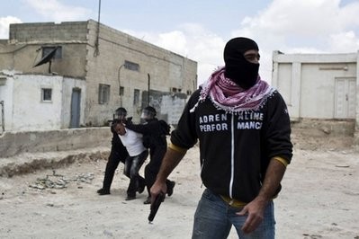 An Israeli undercover policeman holds a gun as riot policemen arrest a Palestinian protester during clashes in the east Jerusalem Arab neighborhood of Issawiya