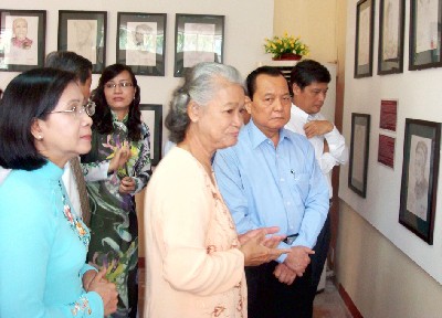 Artist Dang Ai Viet (C, yellow) with city leaders Nguyen Van Dua, (1,R) Le Thanh Hai (2,R) and Nguyen Thi Thu Ha (1,L) in front of her exhibition of pictures of heroic mothers in the Southern Women's Museum (Photo: SGGP)