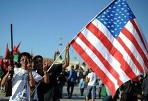 Libyan youths pose with a US flag and a shotgun at Revolution Square in the rebel stronghold of Benghazi.