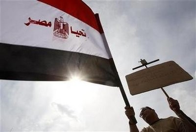 An Egyptian holds up a Koran on a cross and an Egyptian flag that reads Live Egypt during a rally to demonstrate the unity between Muslims and Christians at Tahrir Square in Cairo March 11, 2011